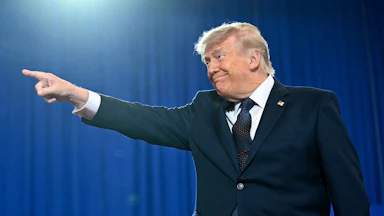 Trump grins as he points a finger to his right