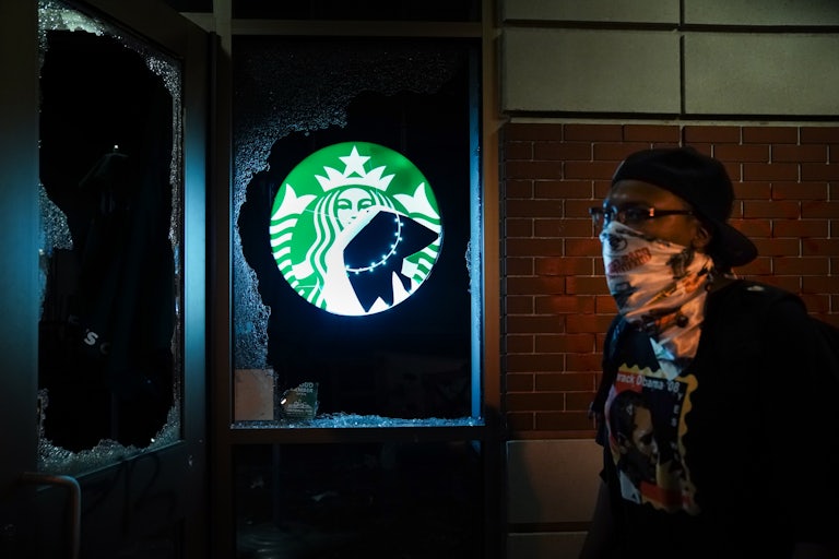 A man walks past a vandalized Starbucks