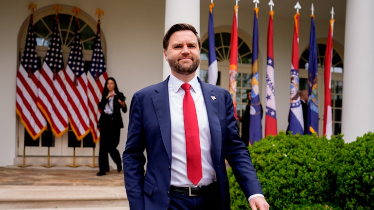 JD Vance strides outside the White House in front of some US flags