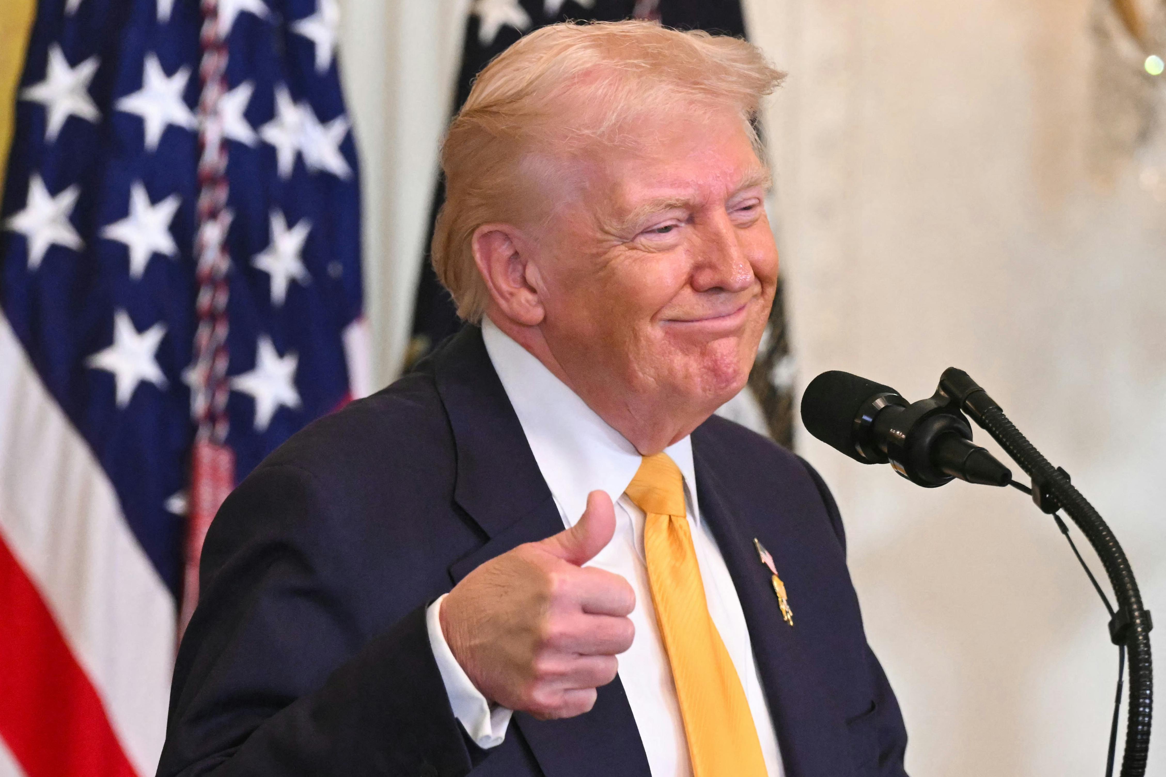 President Donald Trump gives a thumbs up as he speaks during a Black History Month event in the East Room of the White House.