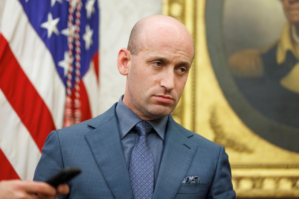 Stephen Miller stands in the Oval Office while Donald Trump signs executive orders