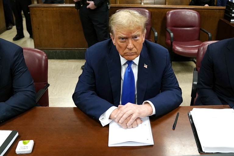 Donald Trump looks up while sitting with his hands folded