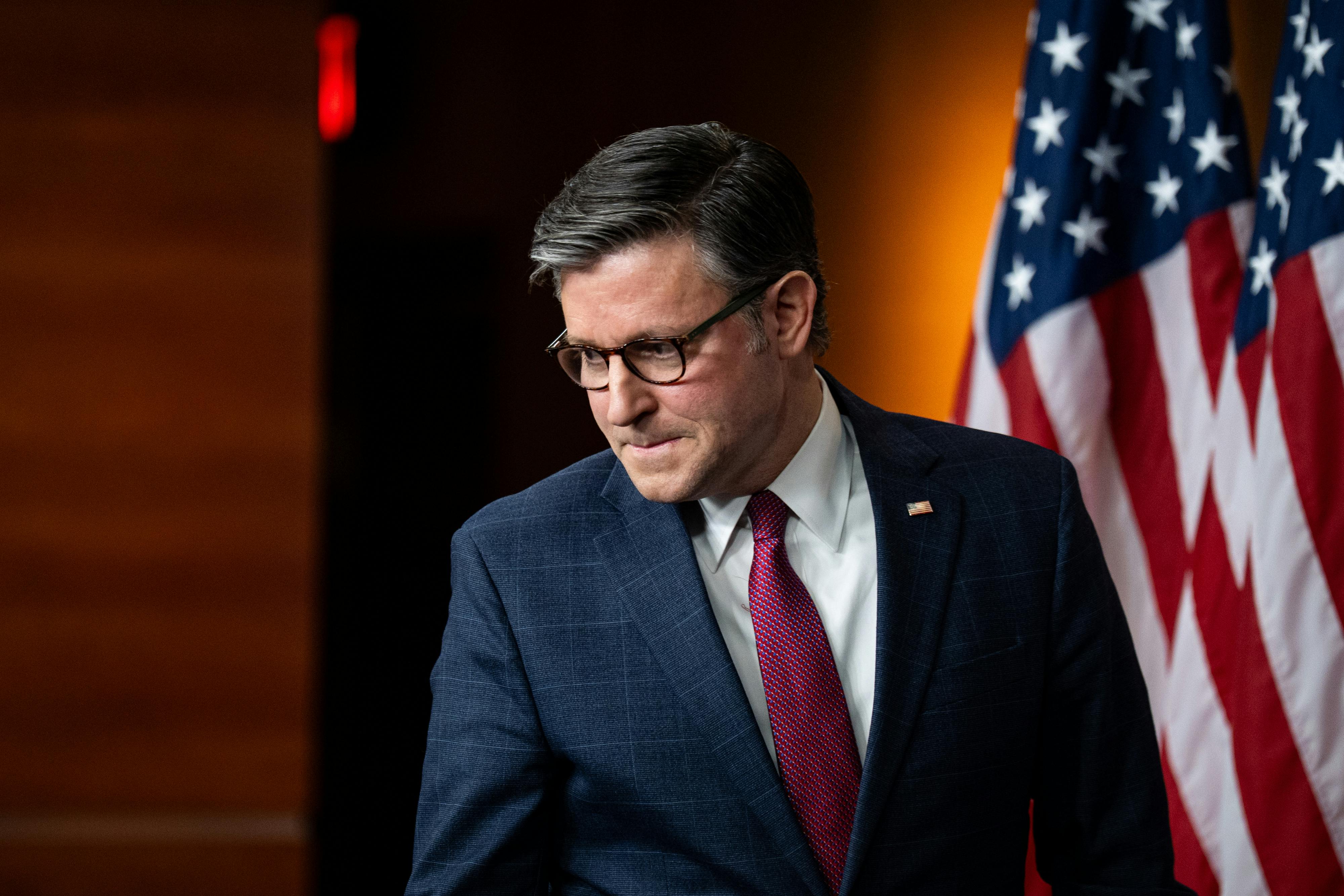 House Speaker Mike Johnson presses his lips together and looks down