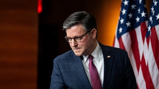 House Speaker Mike Johnson presses his lips together and looks down