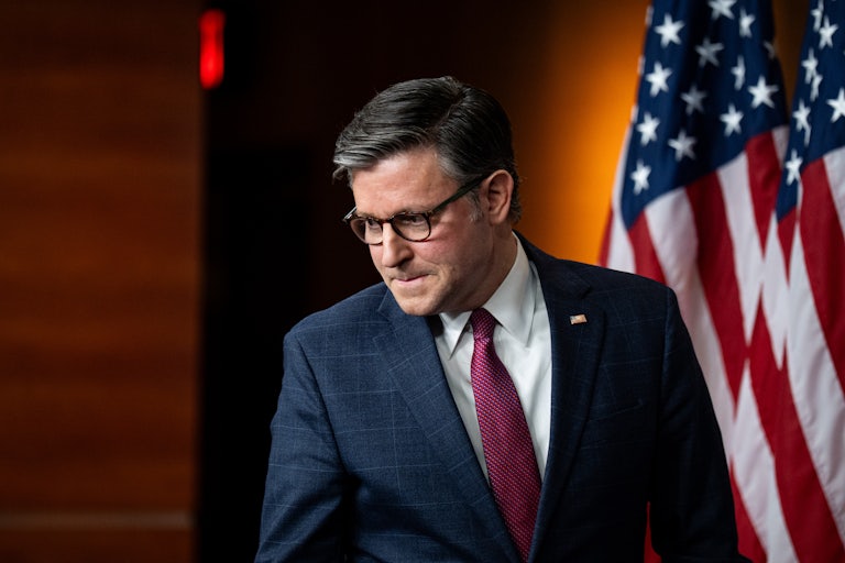 House Speaker Mike Johnson presses his lips together and looks down