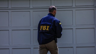 An FBI agents walks near a garage.