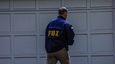 An FBI agents walks near a garage.
