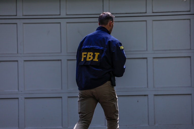An FBI agents walks near a garage.