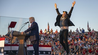 Donald Trump speaks at a campaign rally while Elon Musk jumps behind him