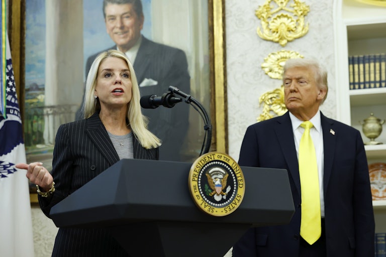 Attorney General Pam Bondi speaks at a lectern in the Oval Office of the White House, while President Trump looks on.