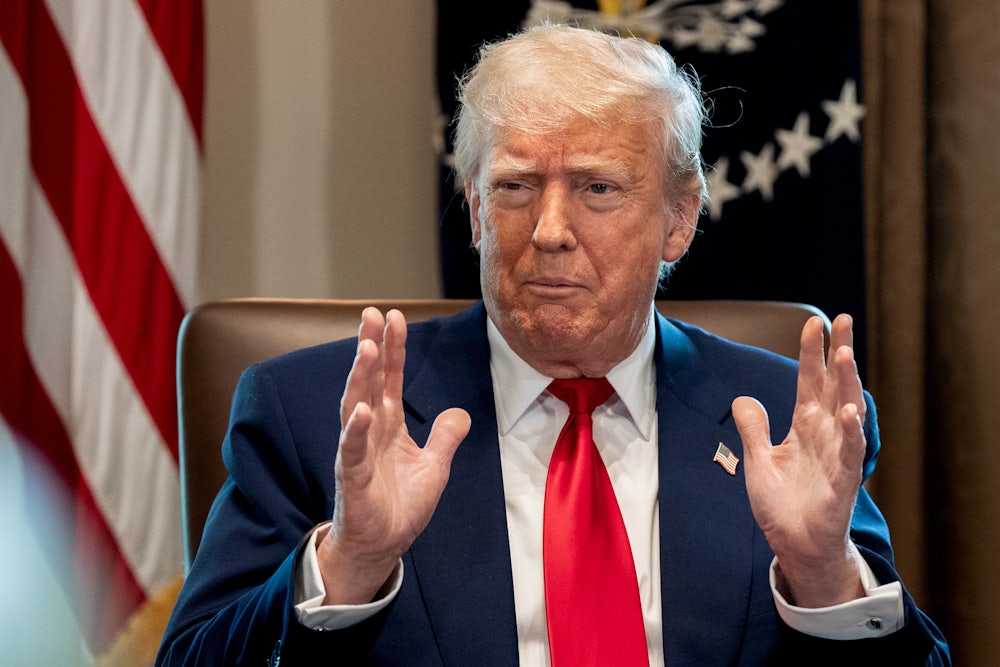 President Donald Trump in close-up holding his hand parallel in front of him.