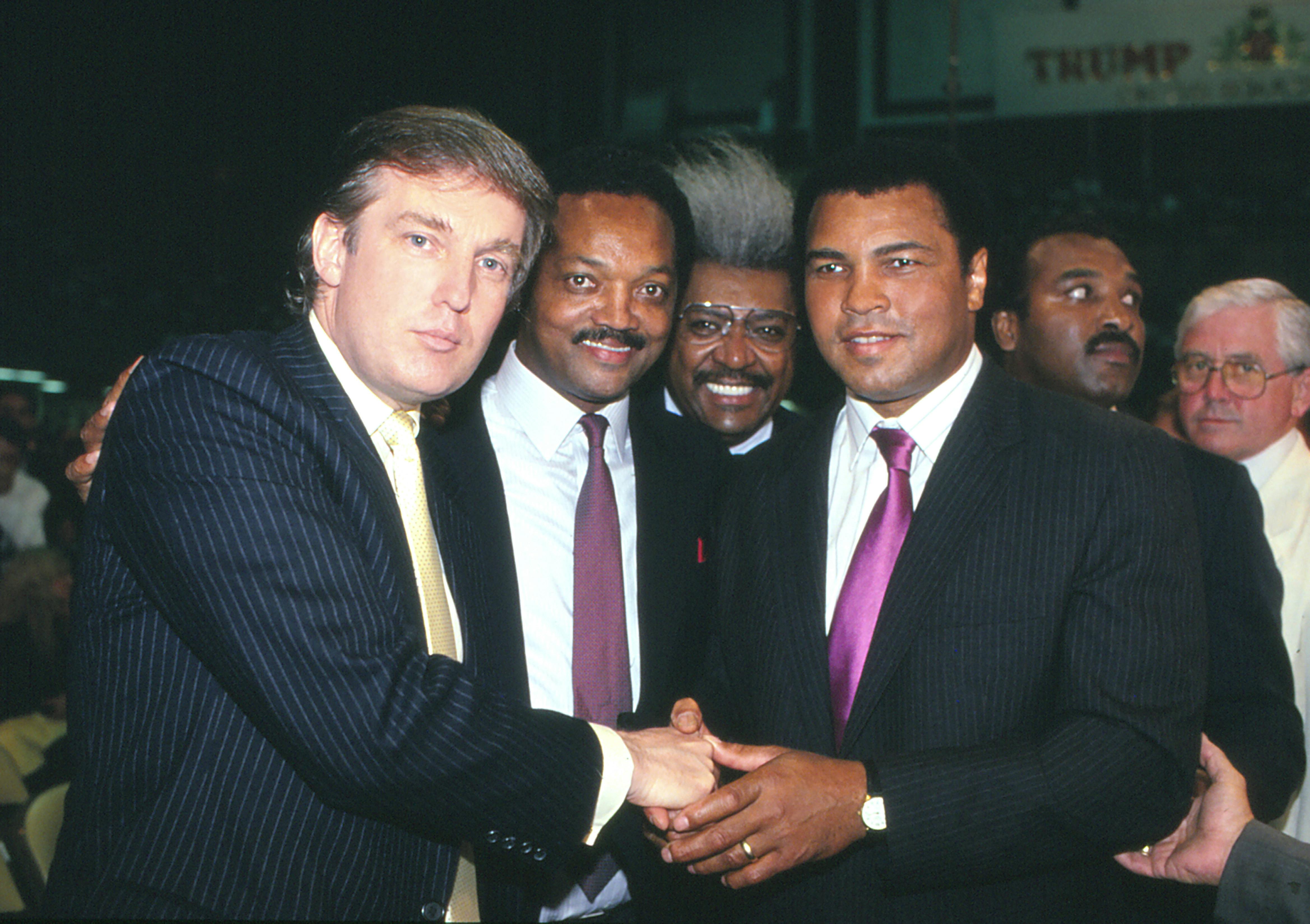 Donald Trump, Jesse Jackson, Don King, and Muhammad Ali smile in a black and white photo.