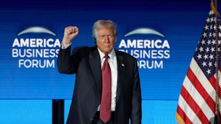 Donald Trump raises his fist while standing on stage at the American Business Forum