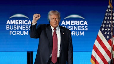 Donald Trump raises his fist while standing on stage at the American Business Forum