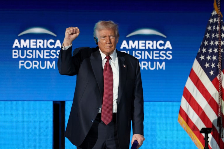Donald Trump raises his fist while standing on stage at the American Business Forum