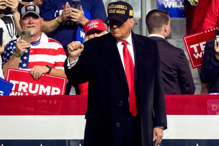 Donald Trump holds up a fist while on stage at a rally