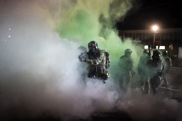 Federal officers walk through tear gas in front of the ICE detention building in Portland, Oregon, in August 2020.