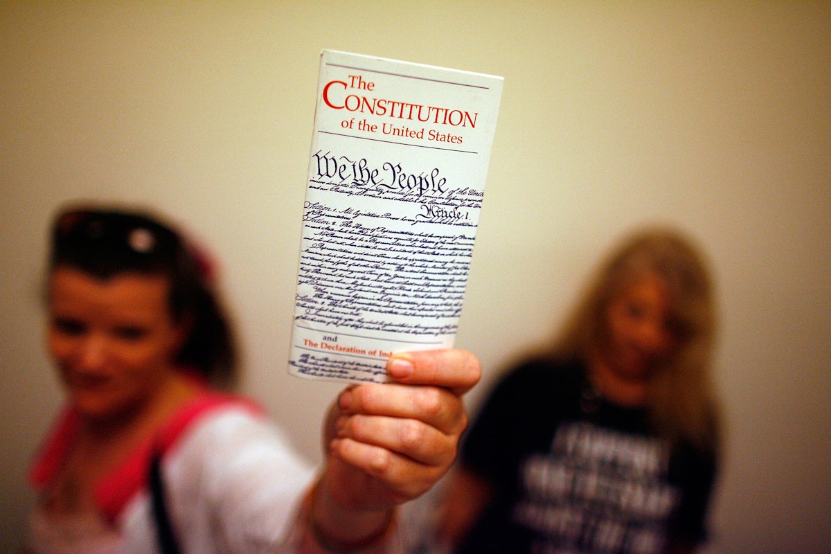 An elementary school teacher holds up a copy of the U.S. Constitution