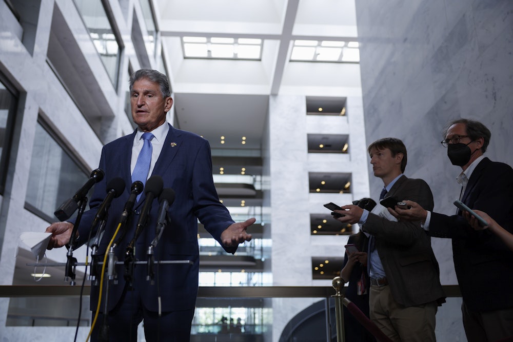 Joe Manchin gestures while speaking to reporters.