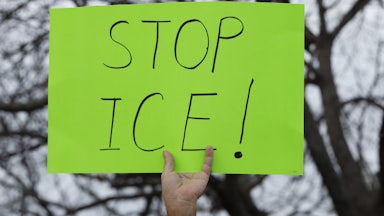 A person holds up a sign that says, "Stop ICE!"