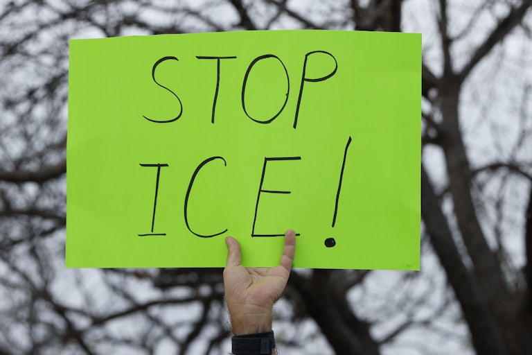 A person holds up a sign that says, "Stop ICE!"