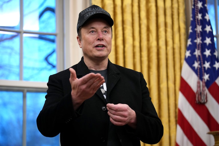 Elon Musk makes a hand gesture while speaking in the Oval Office.