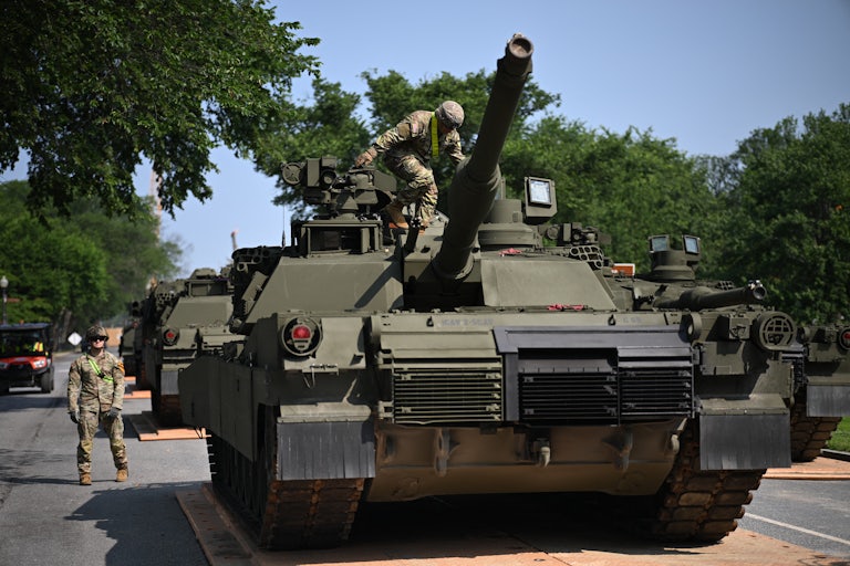A soldier stands on an M1 Abrams tank.