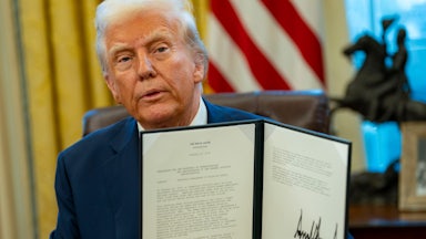 Donald Trump holds up a signed executive order.
