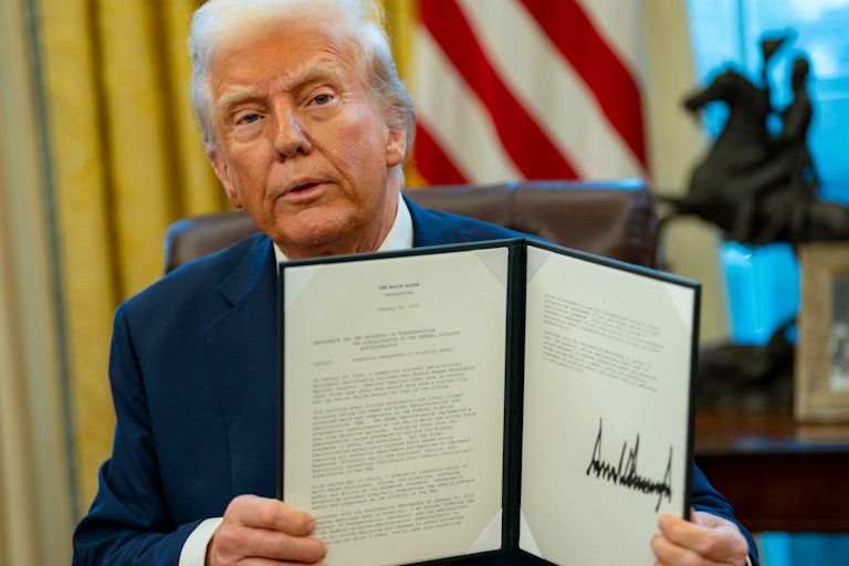 Donald Trump holds up a signed executive order.