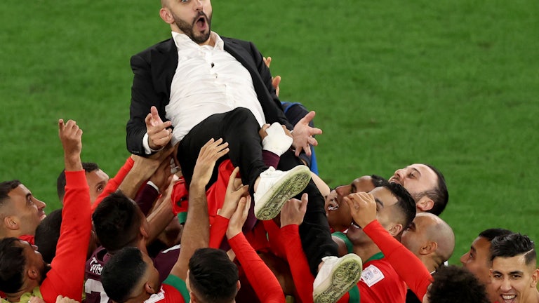 Morocco men’s national team head coach Walid Regragui celebrates with players after their penalty shoot-out win over Spain.