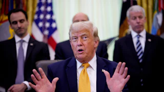 Donald Trump speaking at his desk in the Oval Office of the White House, while others stand behind him.