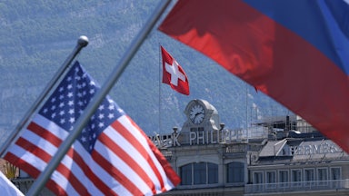 A Swiss flag flies behind Russian and American flags in Geneva