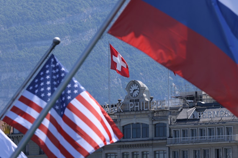 A Swiss flag flies behind Russian and American flags in Geneva