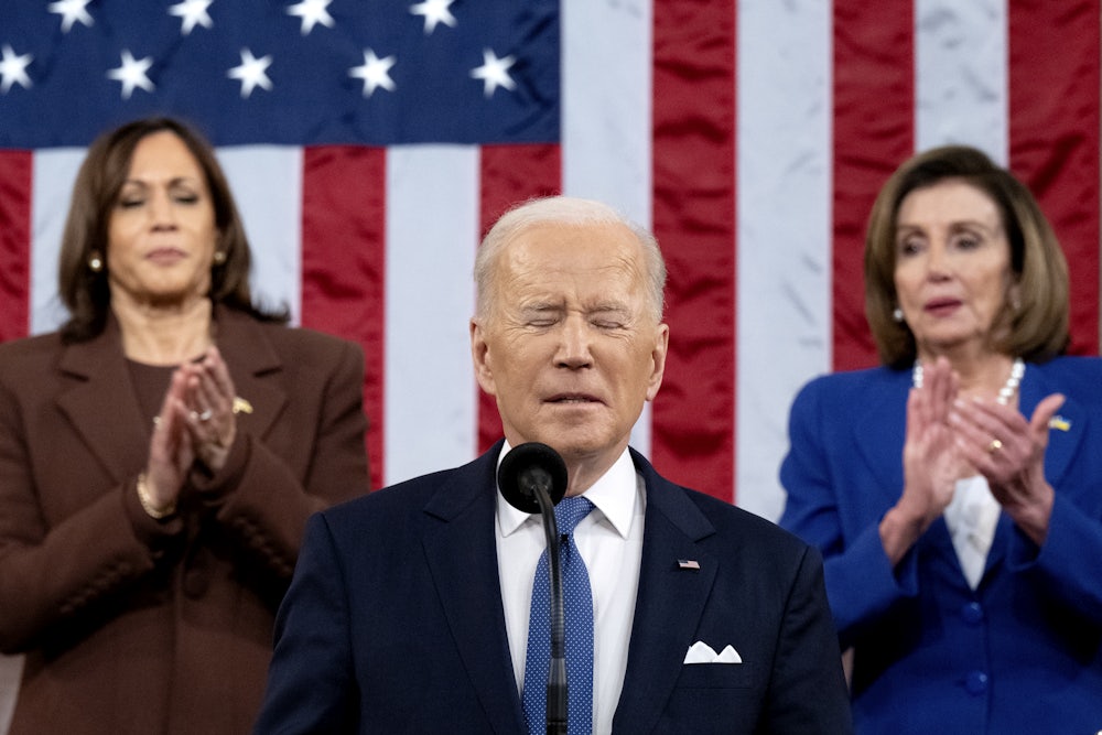 Joe Biden grimaces and closes his eyes as Nancy Pelosi and Kamala Harris applaud.