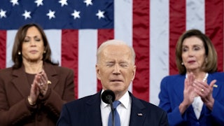 Joe Biden grimaces and closes his eyes as Nancy Pelosi and Kamala Harris applaud.