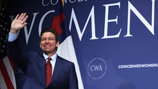 Ron DeSantis waves in front of a sign reading "Concerned Women."