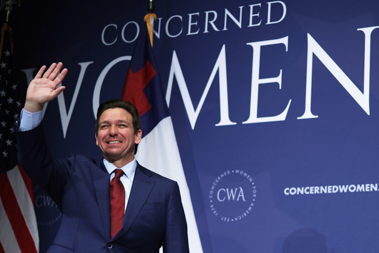 Ron DeSantis waves in front of a sign reading "Concerned Women."