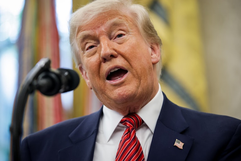 Donald Trump speaks into a microphone in the Oval Office