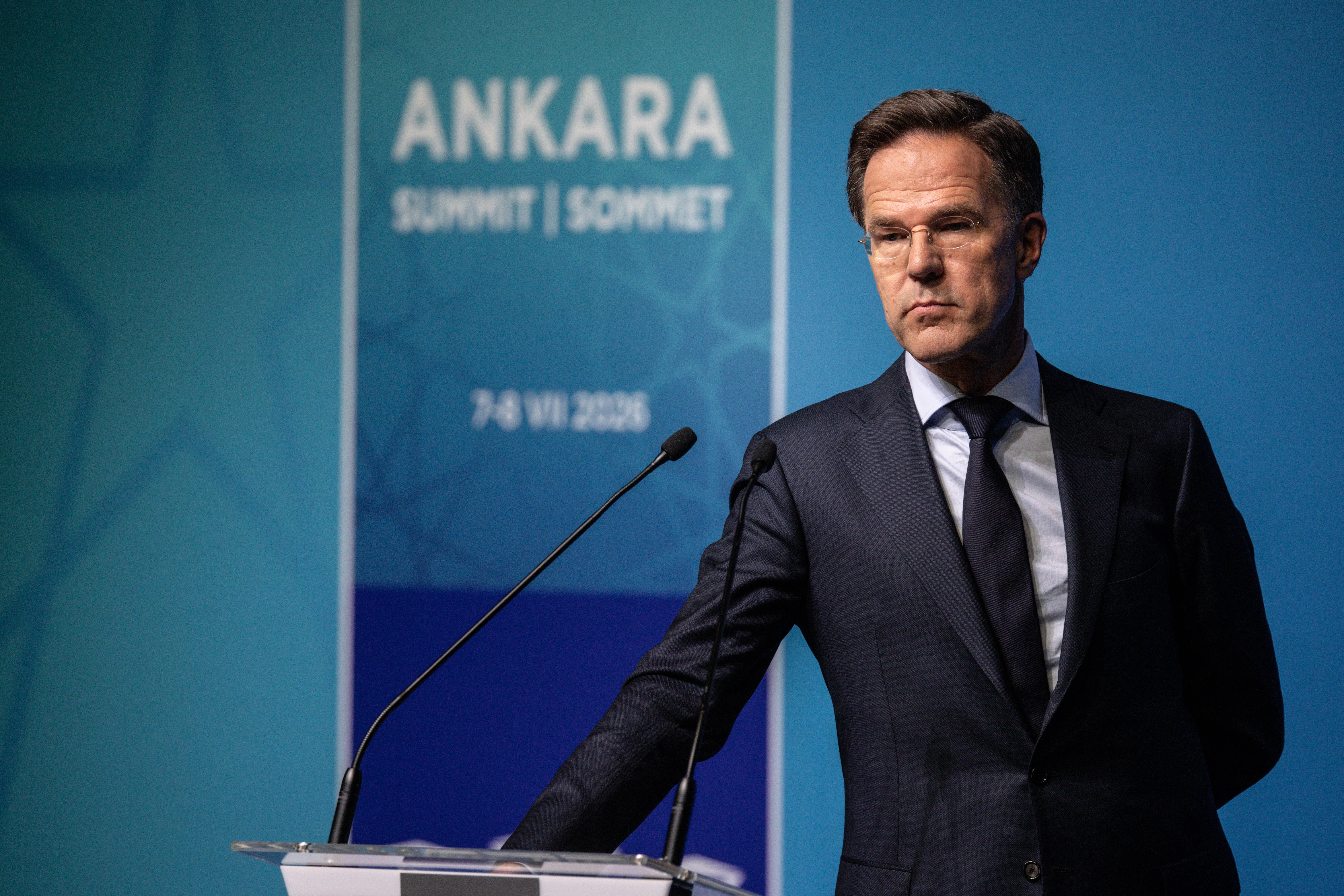 NATO Secretary General Mark Rutte stands next to a podium. He rests one hand on it.