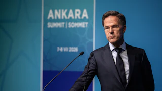 NATO Secretary General Mark Rutte stands next to a podium. He rests one hand on it.