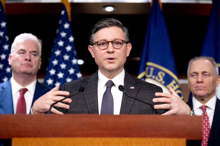 House Speaker Mike Johnson speaks at a podium while flanked by House Majority Whip Tom Emmer and House Majority Leader Steve Scalise