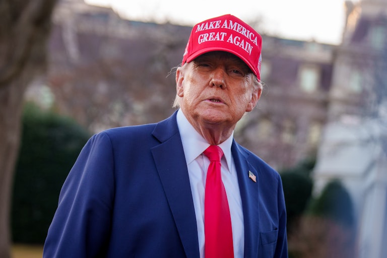 Donald Trump wears a red Make America Great Again cap outdoors.