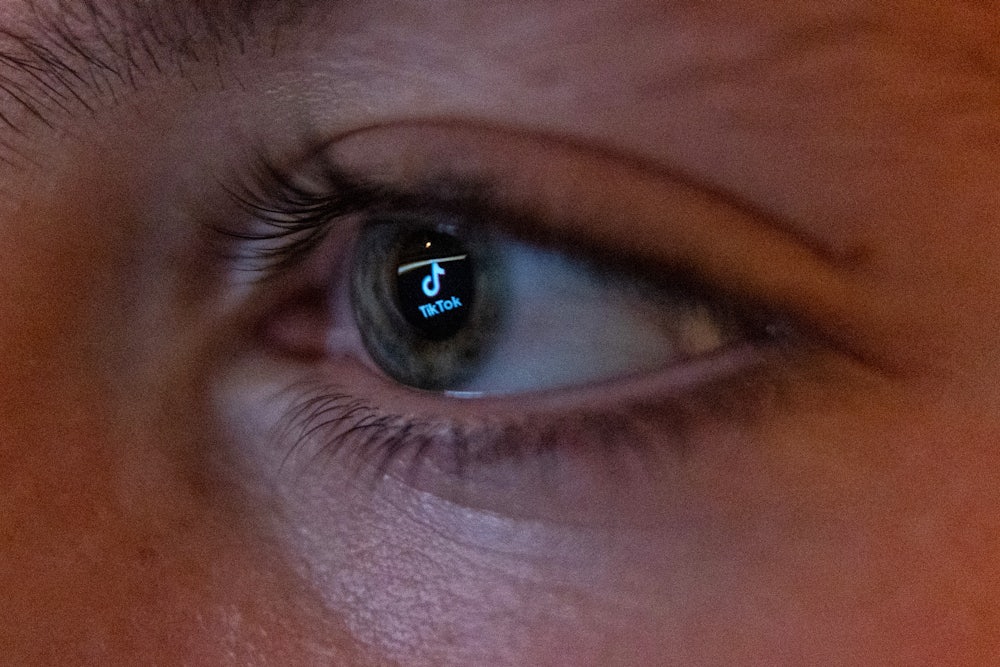 The TikTok social media platform’s logo is reflected in the eye of a 13-year-old boy as he looks at a computer screen.