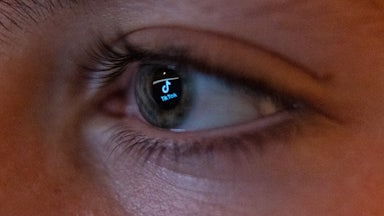 The TikTok social media platform’s logo is reflected in the eye of a 13-year-old boy as he looks at a computer screen.