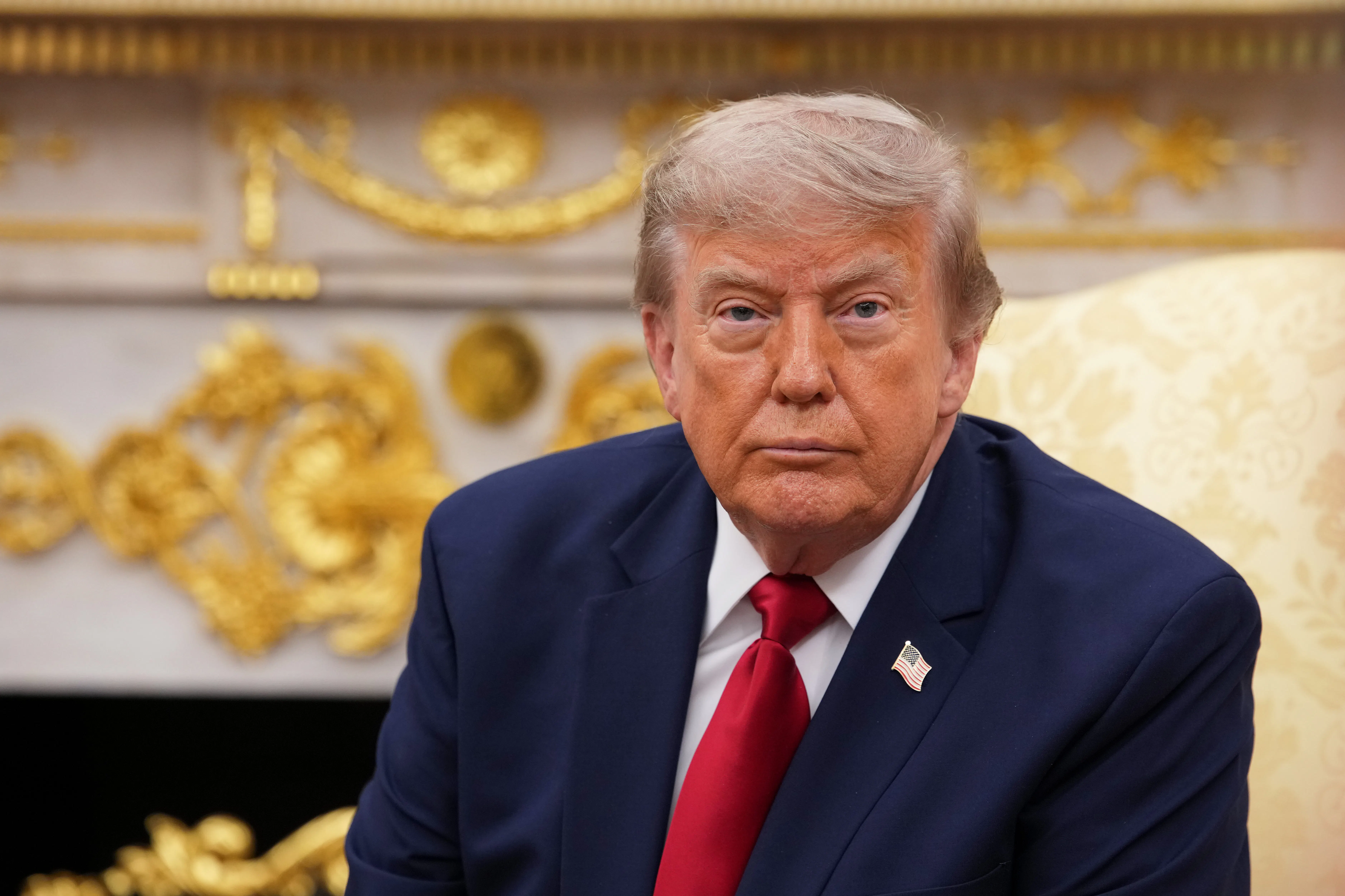 Donald Trump sits in an armchair in the Oval Office.