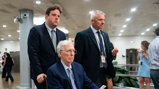 Senator Mitch McConnell is pushed through the Capitol in a wheelchair