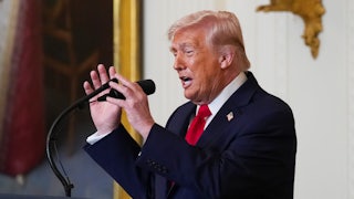 Donald Trump adjusts the microphone while speaking at a podium