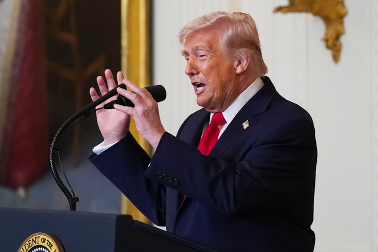 Donald Trump adjusts the microphone while speaking at a podium