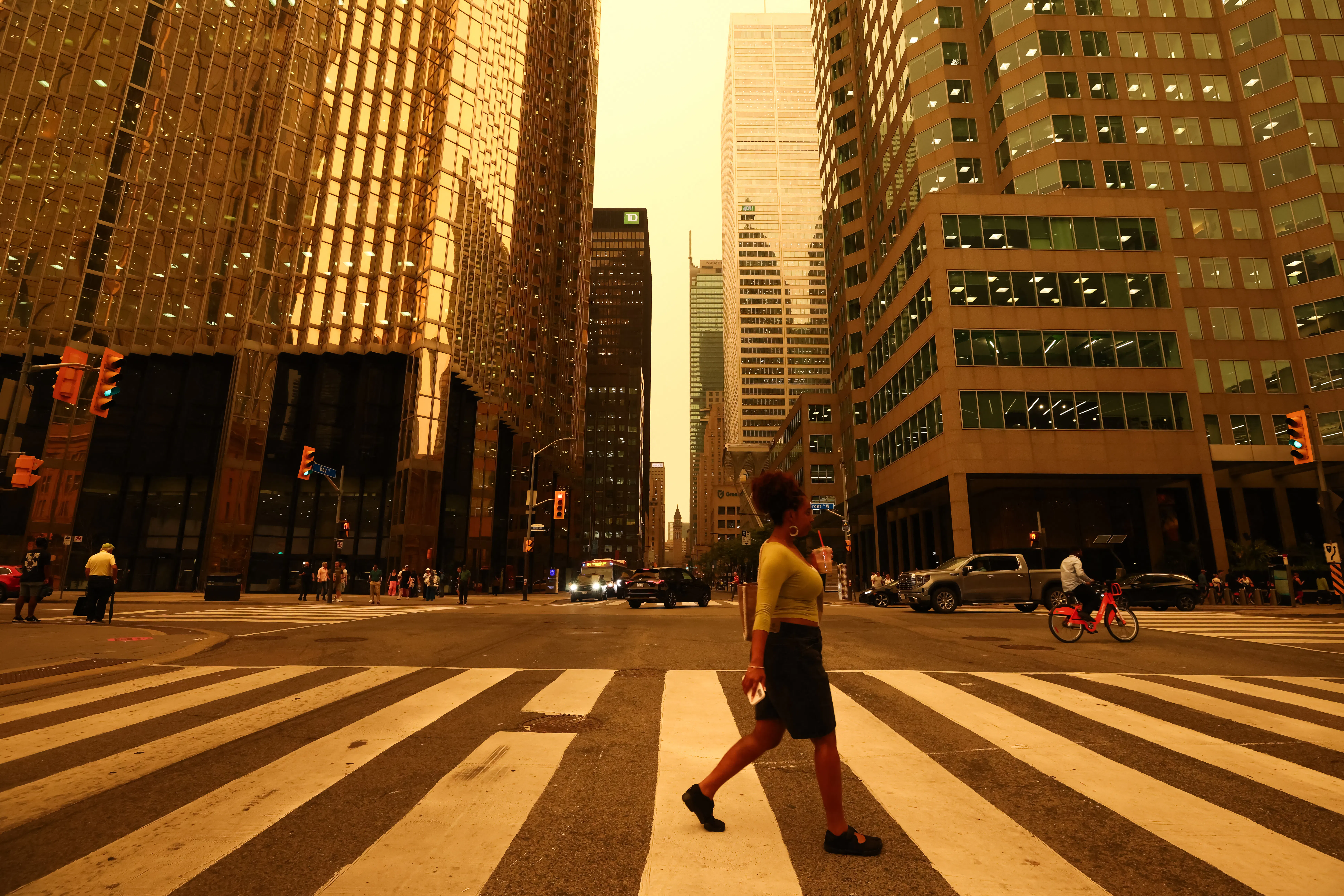 People walk in downtown Toronto, which looks yellow from the wildfire.