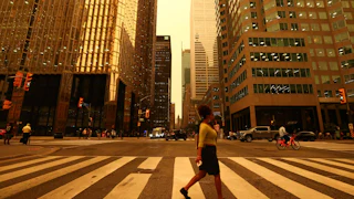 People walk in downtown Toronto, which looks yellow from the wildfire.